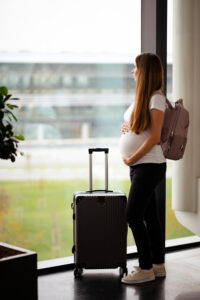 Mujer embarazada en el aeropuerto, lista para volar. Conoce si es peligroso volar embarazada, qué cuidados tomar y cuándo es seguro viajar en avión.